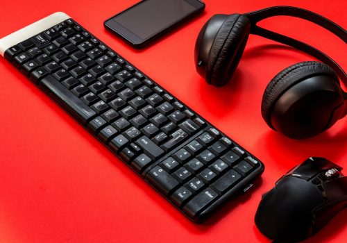 Game keyboard, headphones, mouse accessories for a gamer on a red background. flat lay top view with