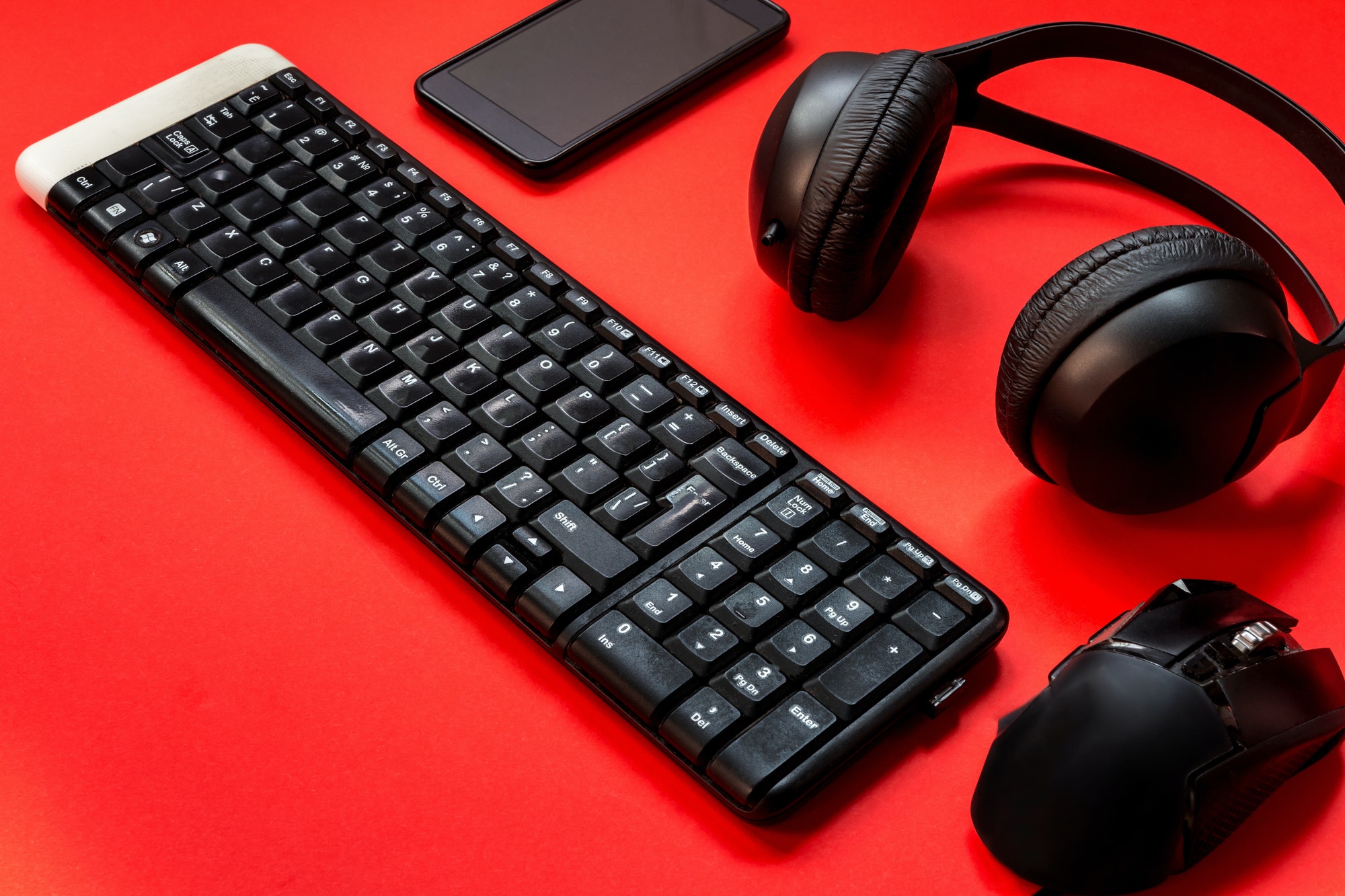 Game keyboard, headphones, mouse accessories for a gamer on a red background. flat lay top view with