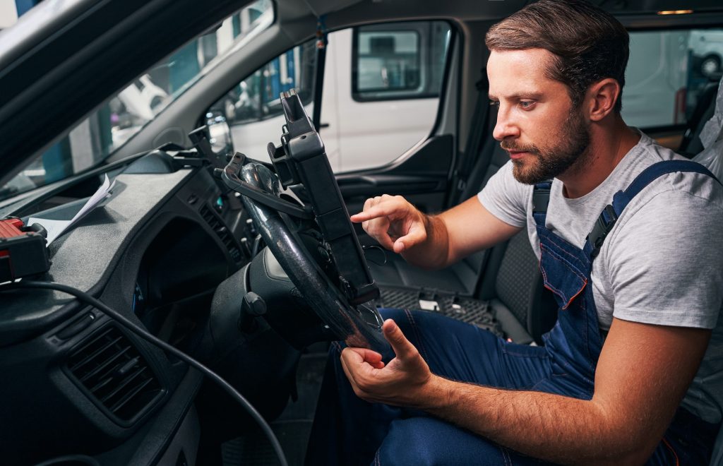Young automotive repairman is scanning car settings